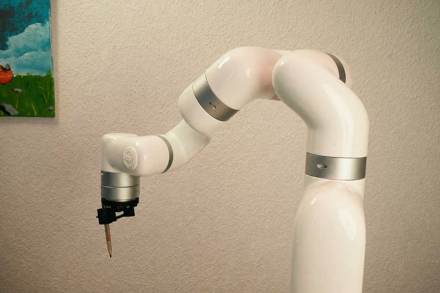 The xArm 7 with pen holder in the studio, a painting on the wall behind